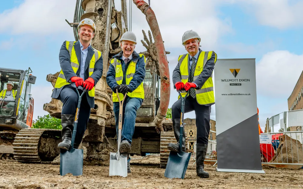 Academics standing pushing spades into the ground at the construction site of the new school of business and management building
