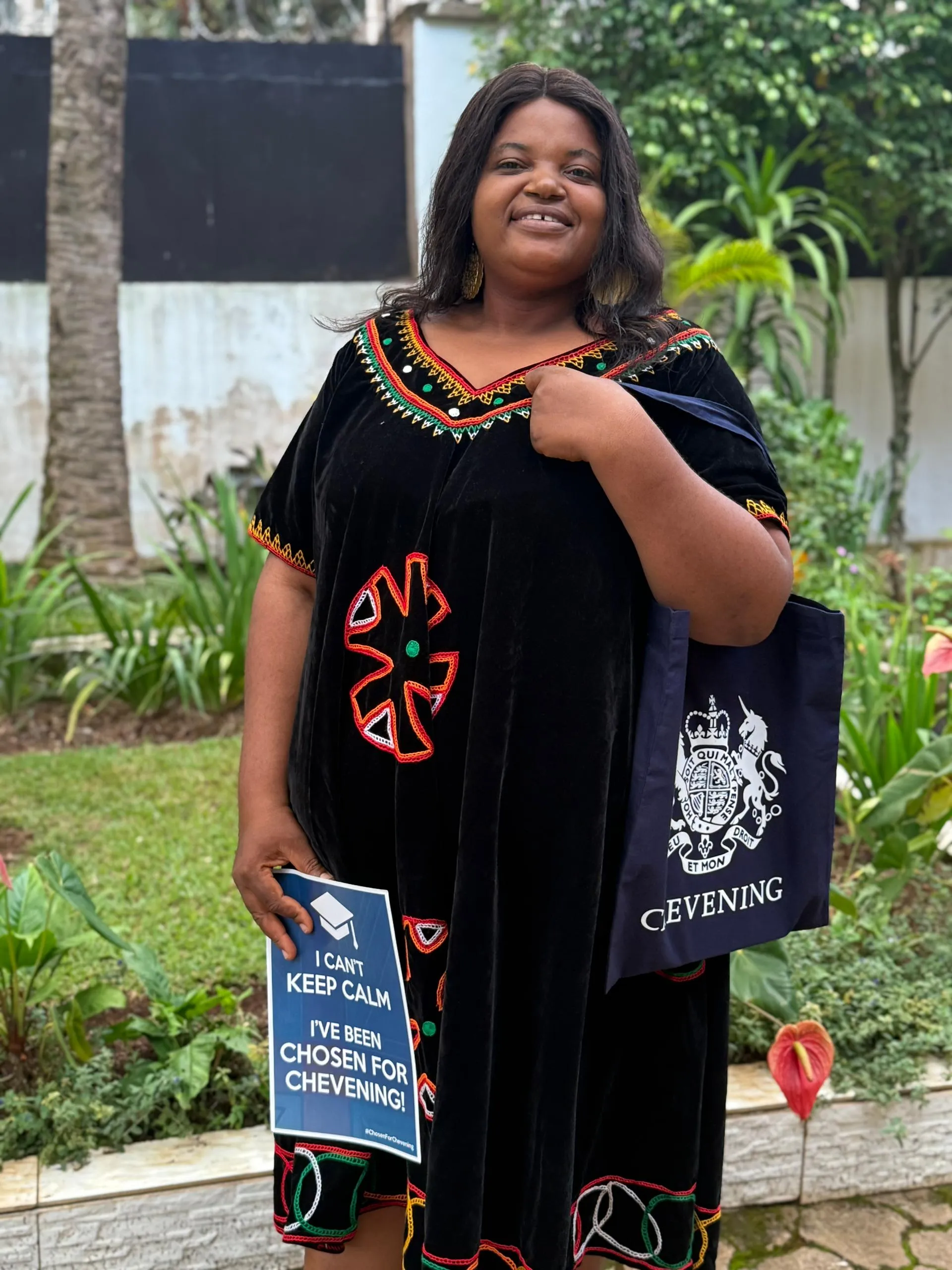 A girl holding a poster and tote bag smiling at the camera
