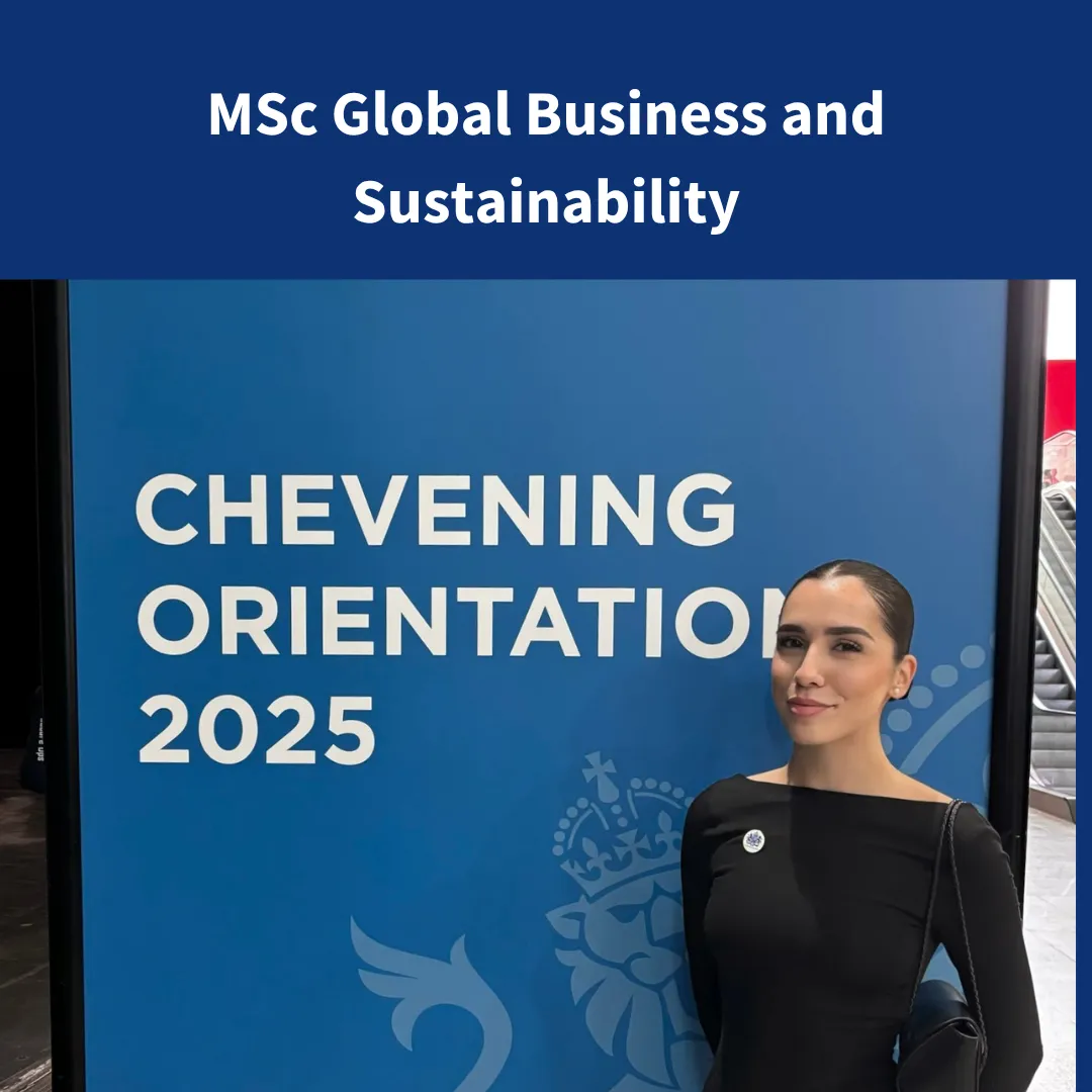 An image of a female with a slick back bun standing in front of a sign saying Chevening Orientation.