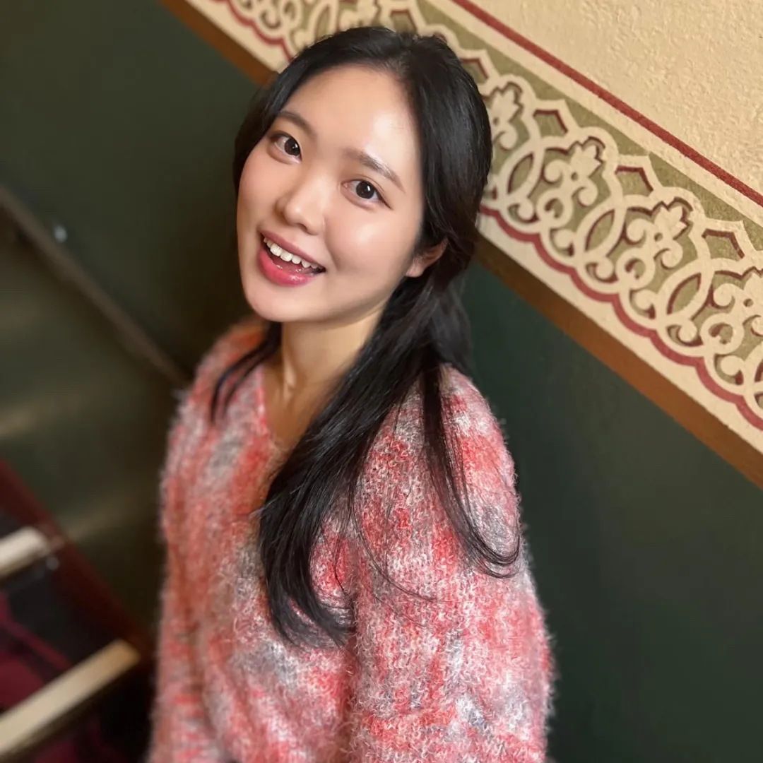 An image of a woman wearing a fluffy jumper standing on a staircase
