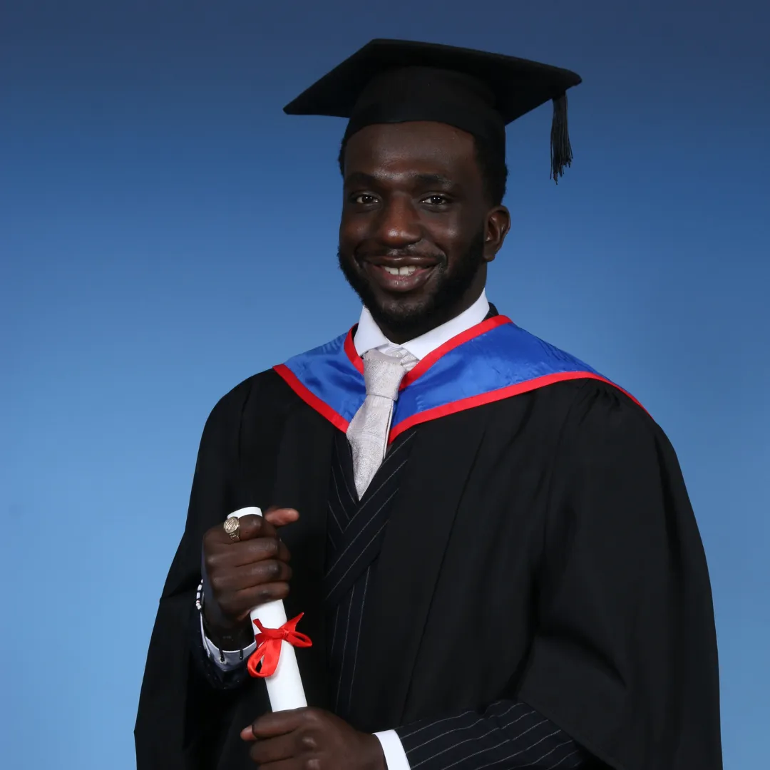 An image of a graduate in cap and gown holding a scroll