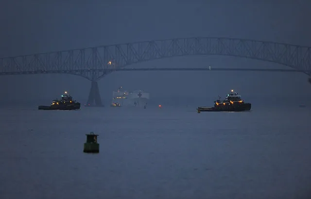 The Francis Scott Key Bridge bridge in Baltimore before it collapsed on 26 March 2024. It is a steel frame truss bridge spanning the lower Patapsco River. There are three ships in the river.