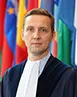 Judge Konrad Marciniak stood in front of country flags.