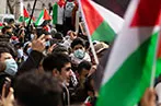 A protest for Palestine in London, with people wearing masks and holding Palestinian flags.