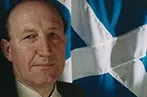 Neil MacCormick with the Scottish flag behind him.