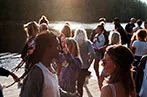 A party of people gathered by a river at sunset