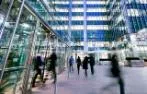 Commuters walking in and out of a London glass-fronted office building.