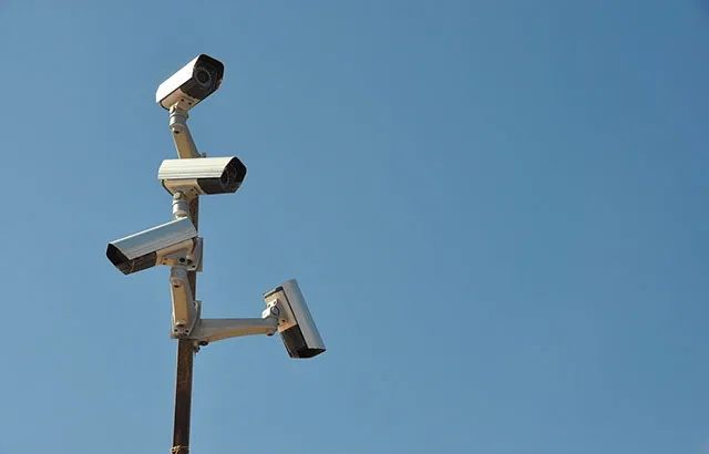 Surveillance cameras on a mast against a blue sky