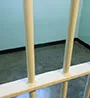 Looking through prison bars into an empty cell.