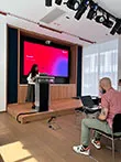 A student standing at a podium in front of a projection screen