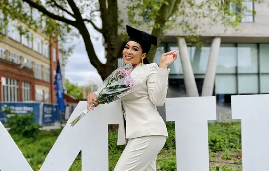 A woman wearing a graduate cap with a bouquet of flowers.