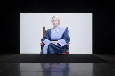 A blonde woman in a purple barristers outfit sitting on an antique chair.