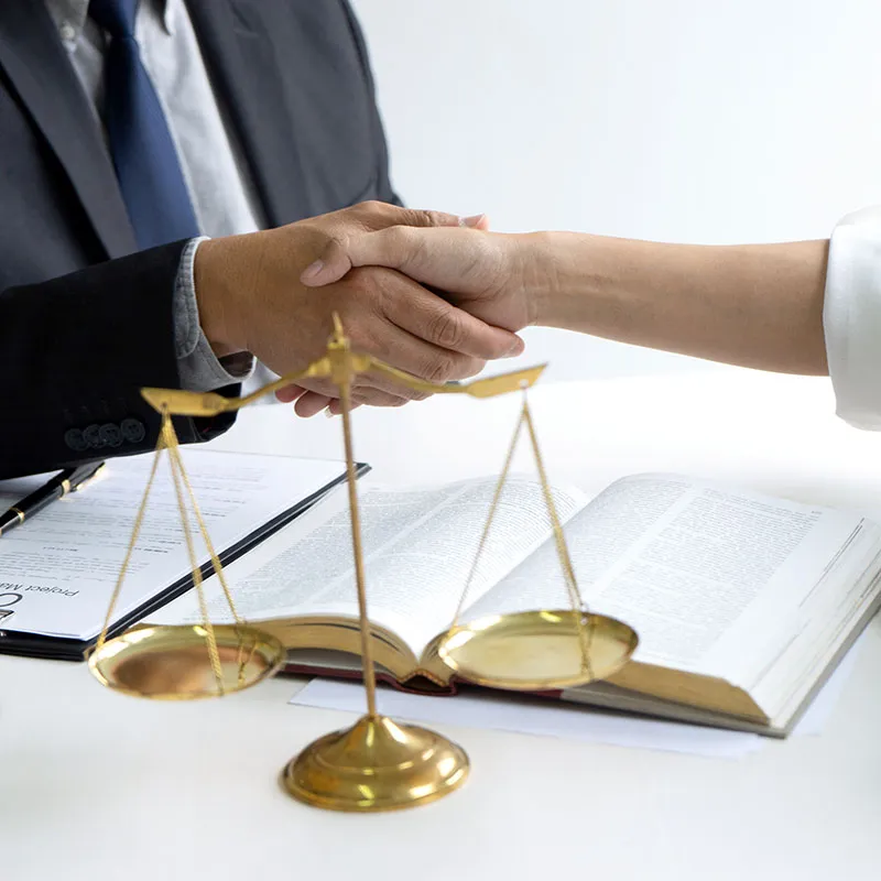A man and woman shaking hands next to a pair of gold scales