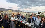 Antigoni Lykotrafiti and Filip Saranovic with Queen Mary LLM alumni on a rooftop bar in Athens at dusk.