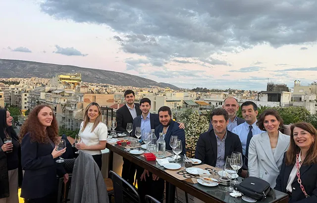 Antigoni Lykotrafiti and Filip Saranovic with Queen Mary LLM alumni on a rooftop bar in Athens at dusk.