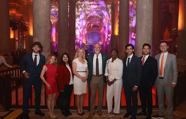 Queen Mary LLM students standing in a pillared hall at the AIEN 2025 conference.