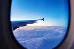 Looking out of an airplane window at a cloudy sunrise.