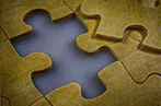 A wooden puzzle, with a missing piece being slotted in