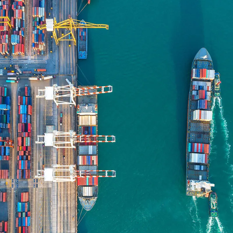 A shipping port with shipping containers and a ship pulling away from the port