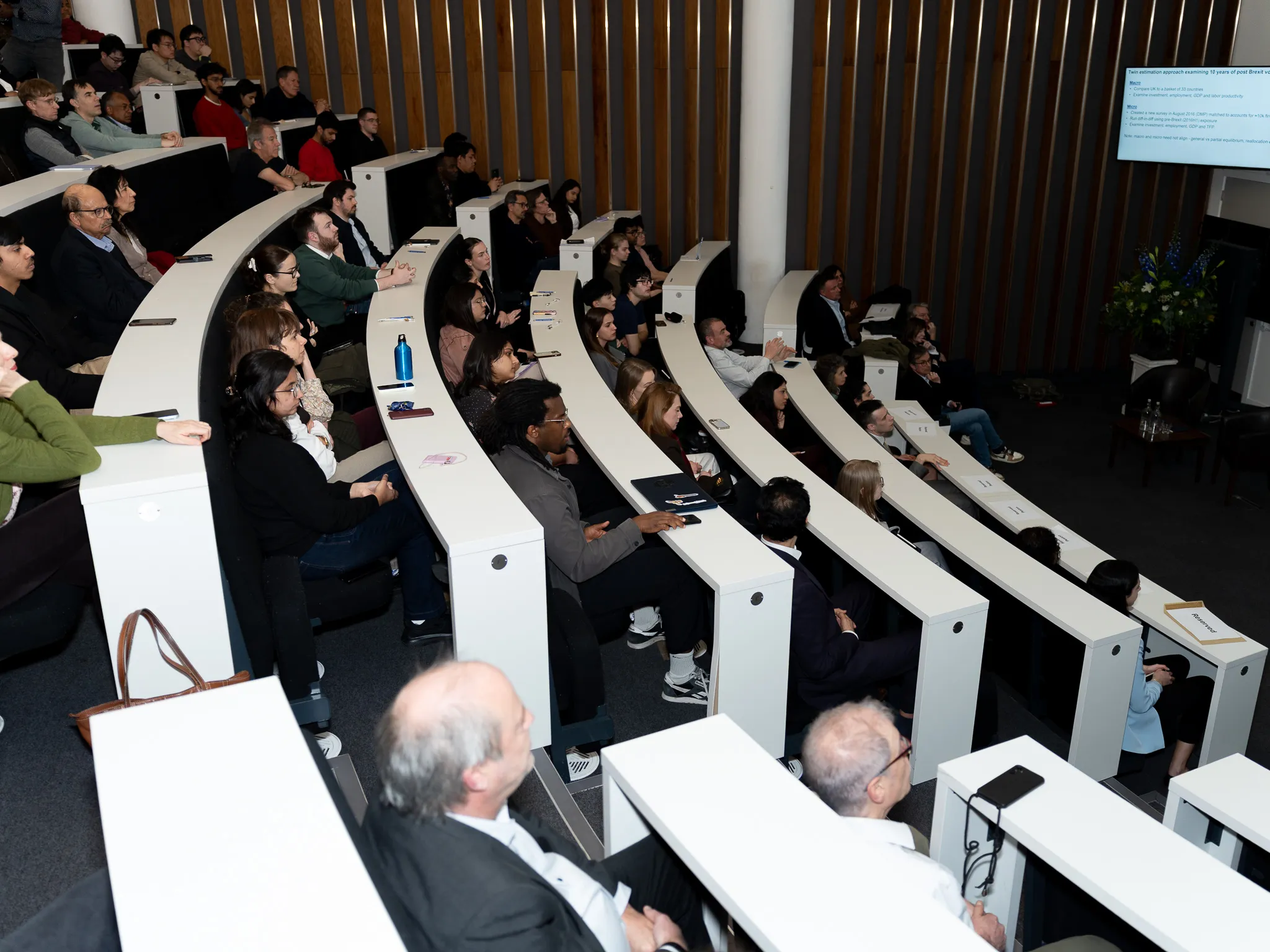 Queen Mary staff students and alumni attending an economics lecture.