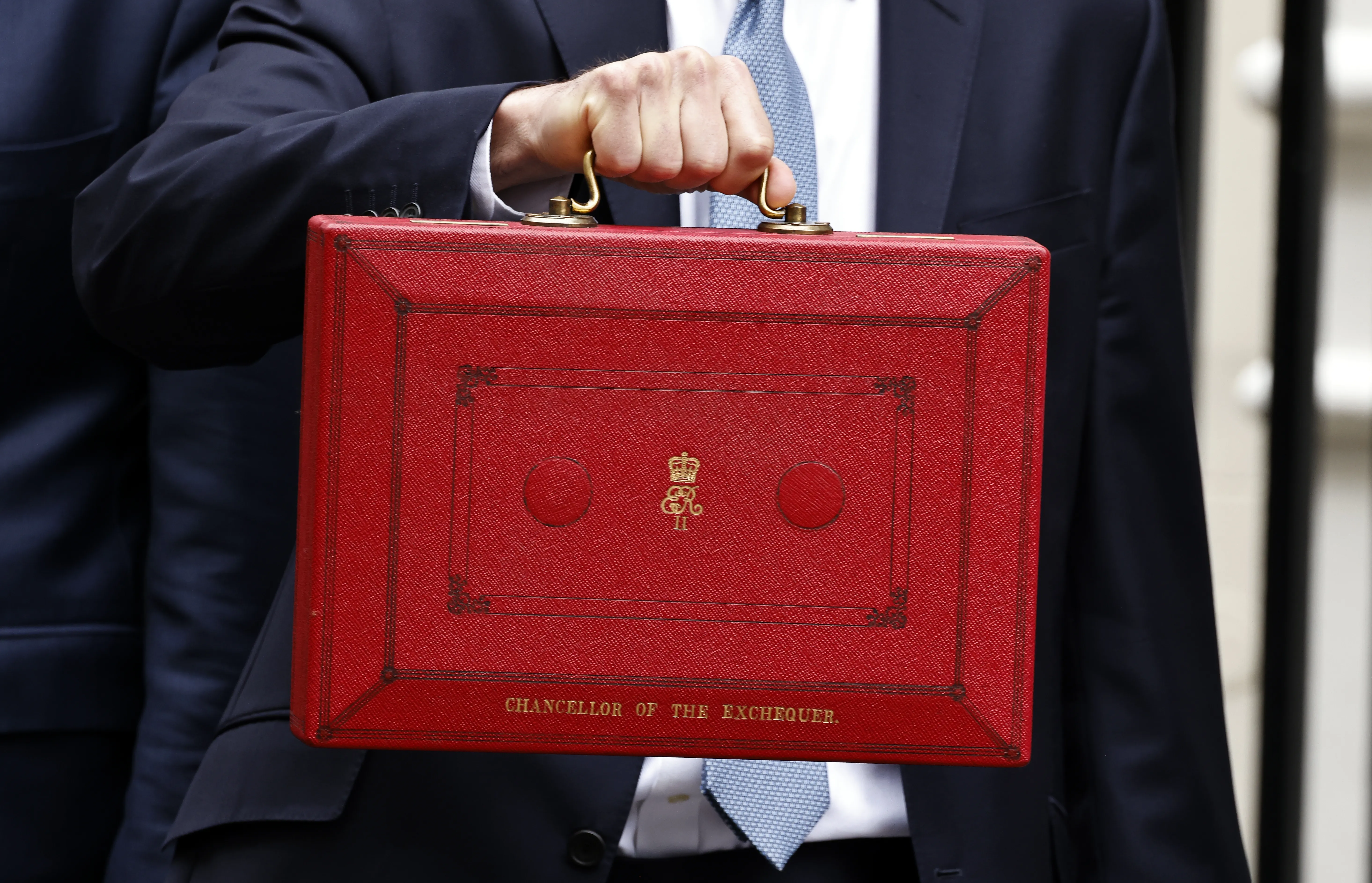 Jeremy Hunt MP, Chancellor of the Exchequer, holds the red box containing the budget. It is zoomed in so you can only see his hand and the Red Box.