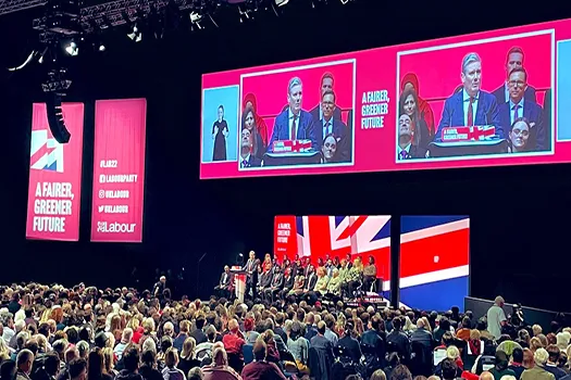 Photo of Keir Starmer's speech at the Labour Party conference in 2022. It is taken from the back of the auditorium and shows the audience listening to Keir Starmer