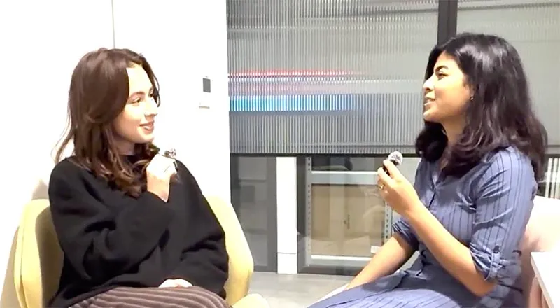 Lily Stuart (BA Drama) and Mrinalini Sarkar (MSc Cancer and Clinical Oncology) sitting on chairs in an office having a conversation