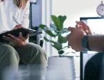 Female therapist writing notes while in session with a male patient.
