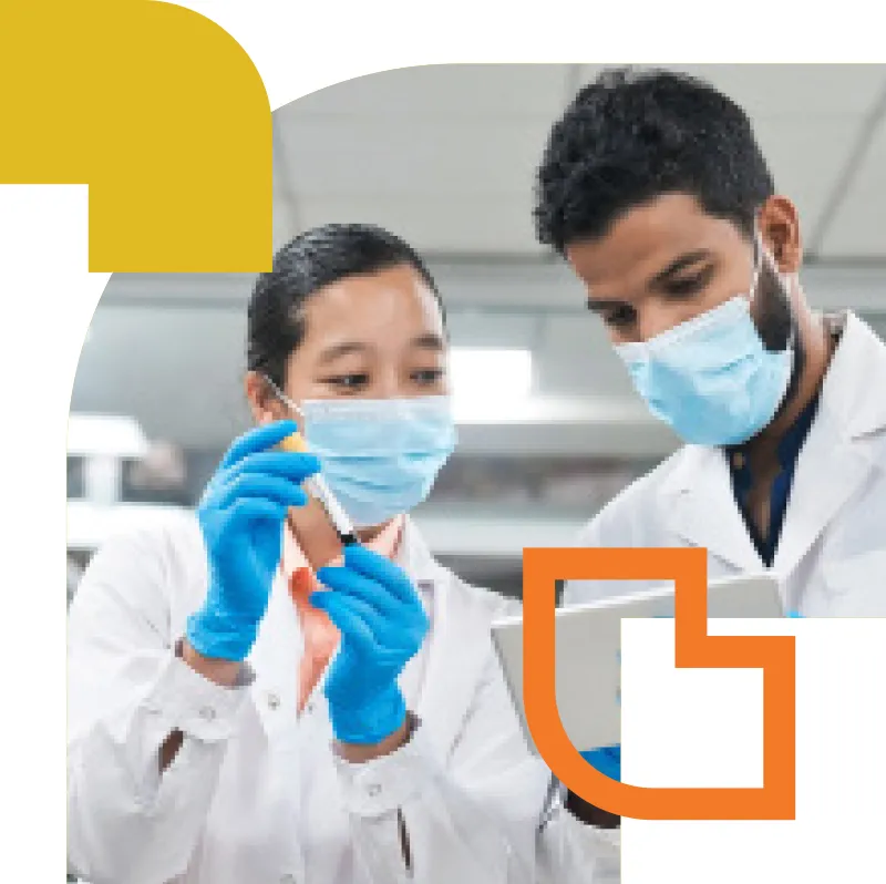 Two researchers wearing masks and gloves examining a sample in a laboratory