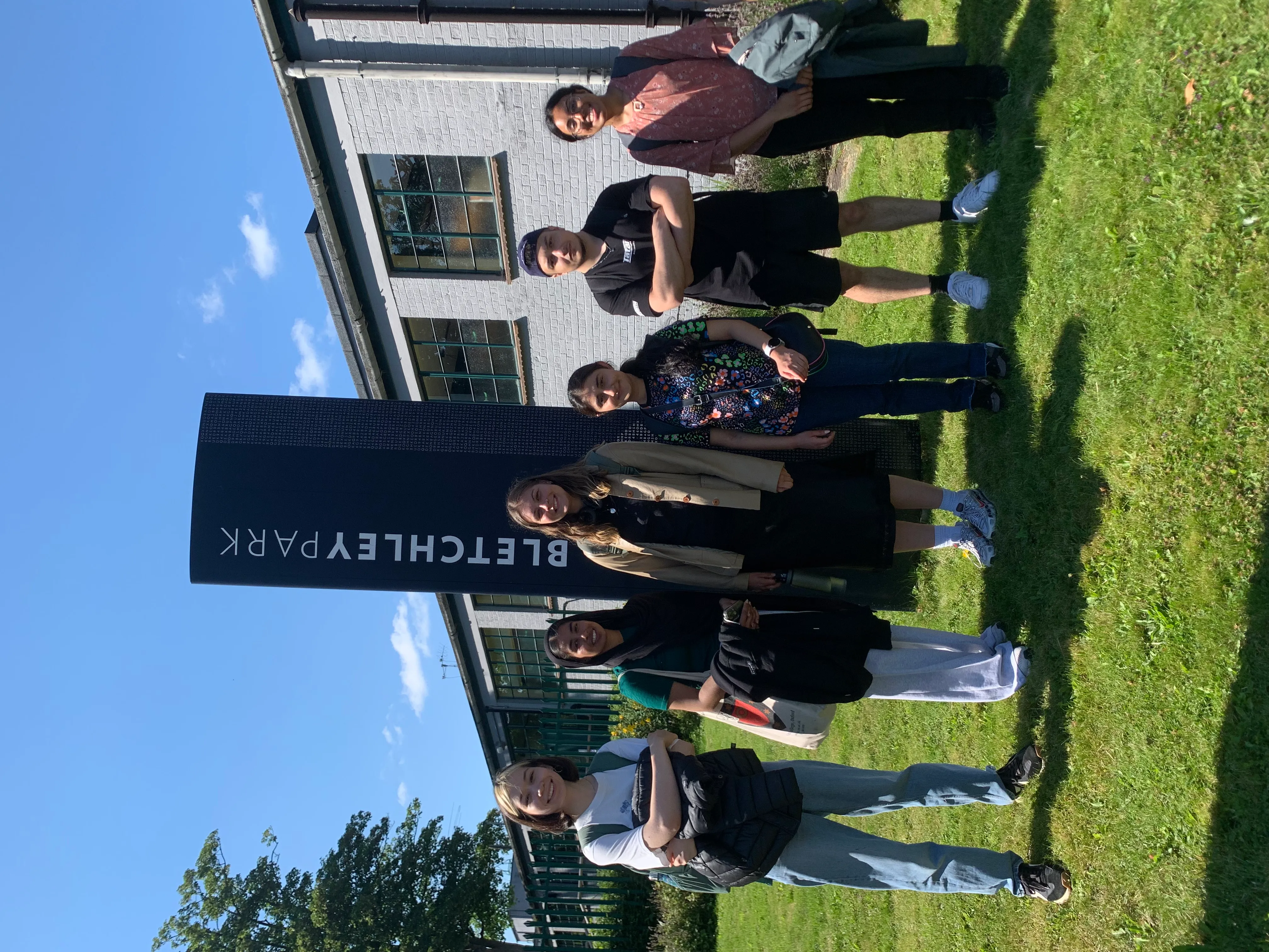 6 undergraduate students starting in front of the Bletchley Park sign on a sunny day