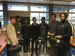 Group of students facing the camera holding cases