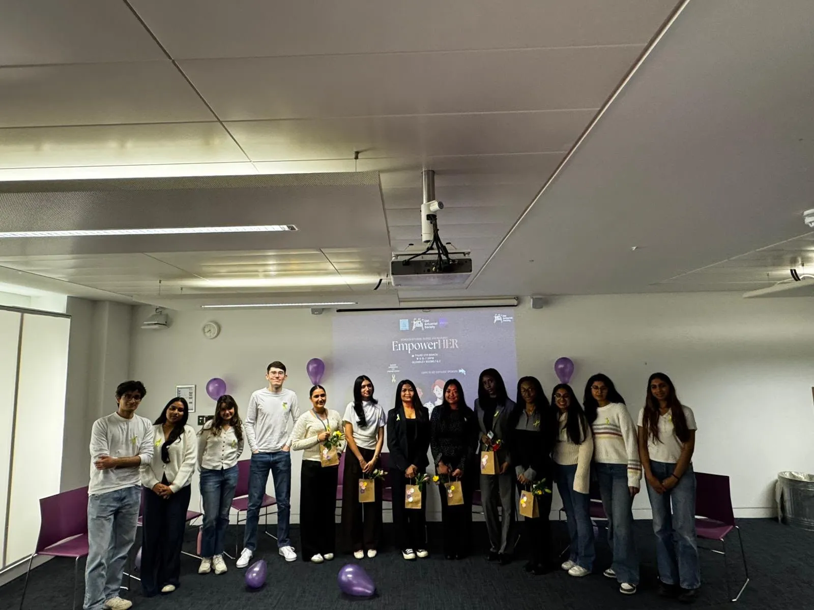A group of students stand in front of a presentation saying 