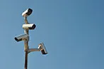 Surveillance cameras on a mast against a blue sky