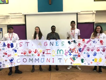 Five Legal Advice Centre Students stand holding a huge colourful banner which reads 