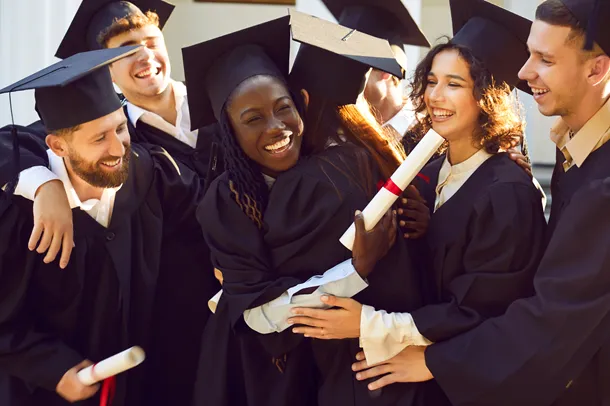 Group of students graduating, holding their certificates and wearing caps and gowns