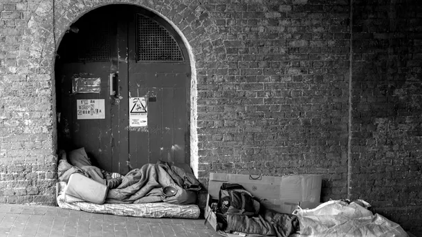 Black and white image of homeless shelters set up in doorway on pavement