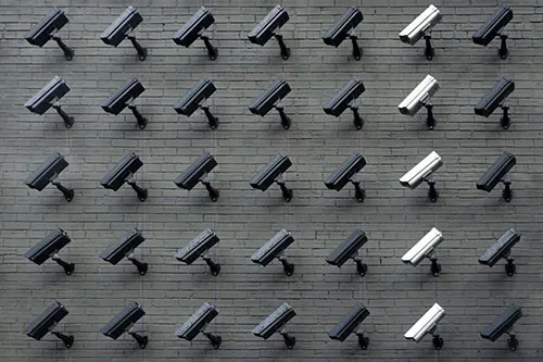 Lines of security cameras arranged on a brick wall