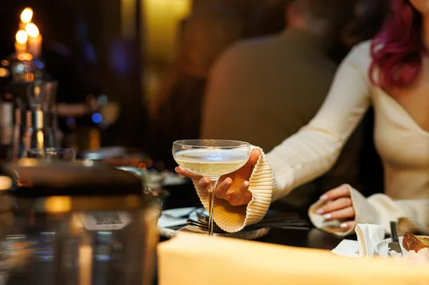 Person reaching for a cocktail at a bar