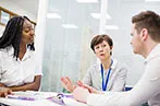 A black woman, a white woman and a white man sat in a meeting room having a discussion