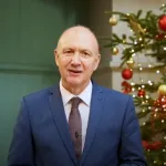 Colin Bailey, President and Principal of Queen Mary University of London, standing in front of a Christmas tree