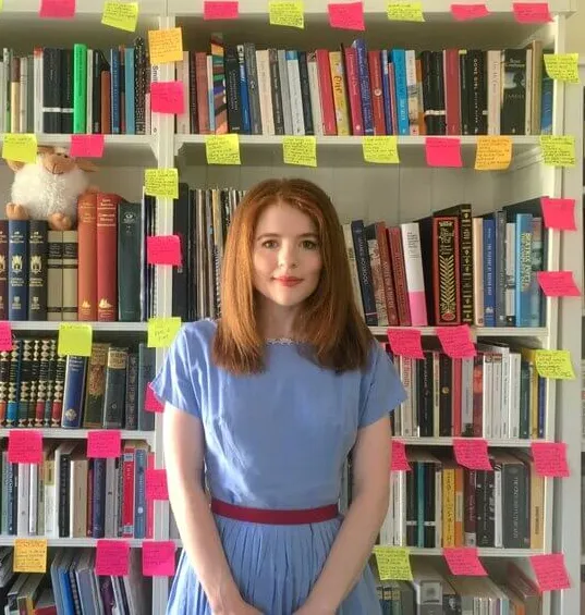 Headshot of alumna Isabel Biggs in front of her bookcase.
