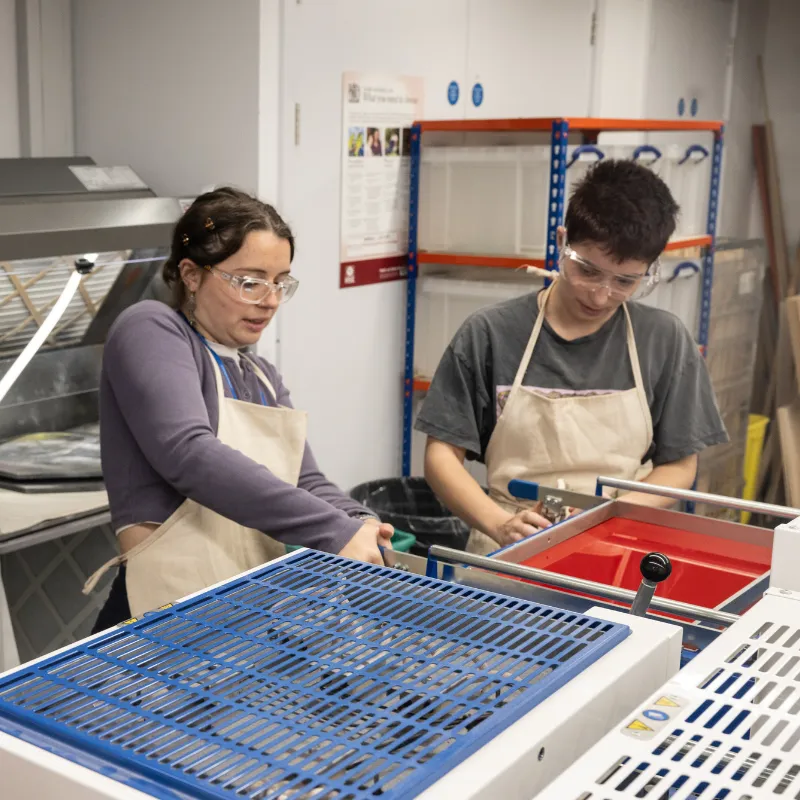 Two students use tools in a workshop
