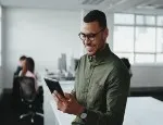 A stock image of a man reading a report on his mobile device 