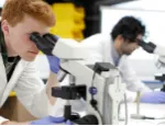 Two students look through microscopes