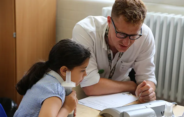 A girl has her lung capacity measured by researcher (2018)