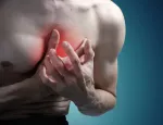 Man clutching chest with both hands, indicating cardiac discomfort symptoms.