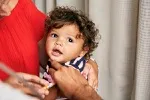 A toddler recieves a vaccine in his arm