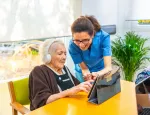Senior woman and nurse using digital tablet and headphones