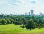 London skyline with green trees and grass in foreground