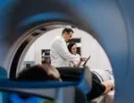 Person in a CT scanner with doctors reviewing film